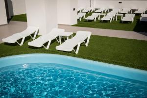 
a pool with chairs and lawn chairs in it at Hotel Melina in Benidorm

