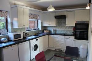 a kitchen with white cabinets and a washer and dryer at Potters House Coventry warwickshire in Coventry