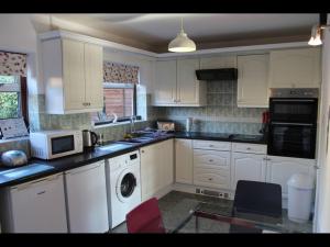 a kitchen with white cabinets and a washer and dryer at Potters House Coventry warwickshire in Coventry
