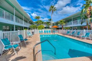 a swimming pool at a resort with blue chairs and palm trees at Tropic Terrace #51 - Beachfront Rental condo in St. Pete Beach