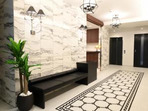 a lobby with a black couch and a marble wall at Amistad Hotel Fukuoka in Fukuoka