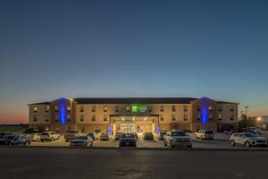 un grand bâtiment avec des voitures garées dans un parking dans l'établissement Holiday Inn Express & Suites N Waco Area - West, an IHG Hotel, à West