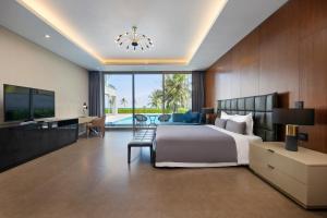 a bedroom with a bed and a television and a pool at Abogo Resort Villas Ocean Da Nang in Da Nang