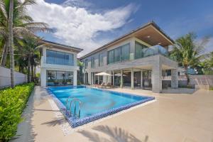 a house with a swimming pool in front of a house at Abogo Resort Villas Ocean Da Nang in Danang