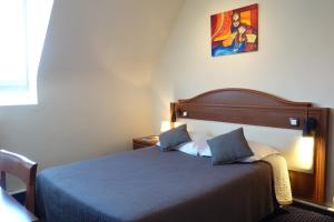 a bedroom with a bed with a blue comforter at Logis Hôtel Central in Montargis