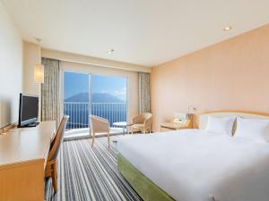 a hotel room with a bed and a large window at Art Hotel Kagoshima in Kagoshima