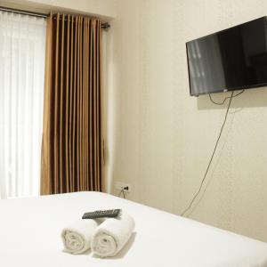 a hotel room with two towels and a television at Spacious Studio Room at Gateway Pasteur Apartment near Exit Toll Pasteur By Travelio in Bandung