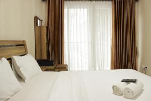a bedroom with a white bed with two towels on it at Spacious Studio Room at Gateway Pasteur Apartment near Exit Toll Pasteur By Travelio in Bandung +7 photos