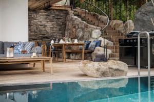 a patio with a table and a grill next to a pool at GipfelKreuzLiebe Senhoog Luxury Holiday Homes in Leogang