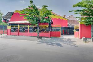 スラバヤにあるSuper OYO Capital O 3198 Sukomanunggal Innのヤシの木が前に立つ赤と黄色の建物
