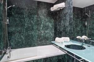 a bathroom with a sink, mirror, and tub at B&B Hotel Jerez in Jerez de la Frontera