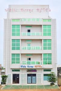 un edificio con un cartello bianco dell'hotel di White Horse Hotel Cotonou a Agblangandan