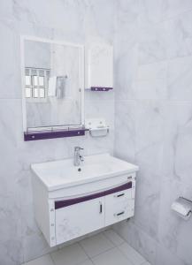 Baño blanco con lavabo y espejo en White Horse Hotel Cotonou en Agblangandan