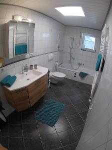 een badkamer met een wastafel, een toilet en een bad bij Ferienwohnung Pusteblume in Wüstensachsen
