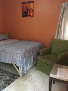 um quarto com uma cama e uma cadeira em Sumanguru Guest House- GATEWAY TO THE AIRPORT em Busumbala