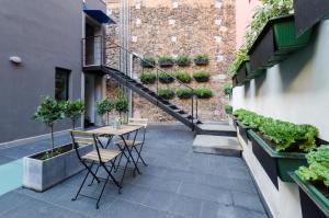 patio con mesa, sillas y pared de ladrillo en Pietranera Apartments, en Catania