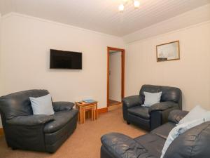 uma sala de estar com 2 cadeiras de couro e uma televisão de ecrã plano em Viola Cottage em Fraserburgh
