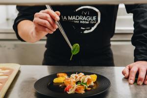 Hôtel Spa Restaurant La Madrague في لوسيانا: شخص يحمل شوكة وطبق من الطعام