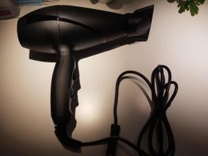 a black hair dryer sitting next to a wall at House By The Beach in Eilat