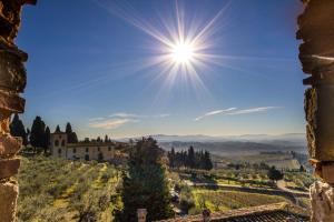 una vista de una villa en una colina con el sol en el cielo en Fattoria di Cinciano, en Poggibonsi