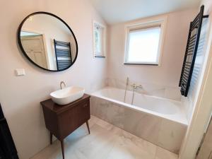 une salle de bain avec une baignoire, un lavabo et un miroir dans l'établissement Cozy historical Cottage (Huisje HèHè), à Wassenaar 34 autres photos
