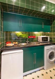 uma cozinha com armários verdes, um lavatório e um micro-ondas em The Broughton Road Residence em Edimburgo