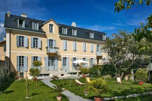 a large white building with a large yard with plants at Le Pigeonnier in Embrun