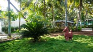 une statue dans l'herbe dans une cour avec des palmiers dans l'établissement RK RESORTS, à Karikal