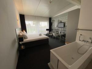 Habitación de hotel con cama y bañera en De Slaapfabriek vakantiehuis en trainingslocatie, en Teuge