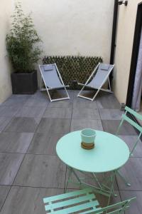 twee vouwstoelen en een tafel en een kopje op een patio bij Les secrets de l'isle in LʼIsle-sur-la-Sorgue