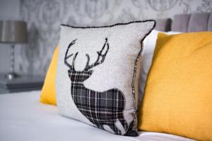 a pillow with a deer on it next to two pillows at McInnes House Hotel in Kingussie