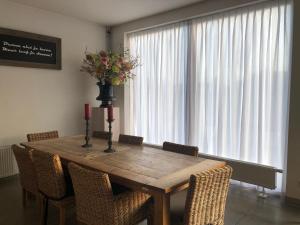 una mesa de comedor con sillas y un jarrón de flores en De Slaapfabriek vakantiehuis en trainingslocatie, en Teuge