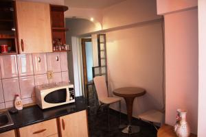 a small kitchen with a microwave and a table at Decebal 1 Premium apartment in Bucharest
