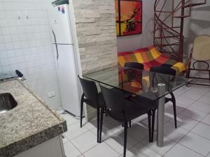 a kitchen with a glass table and chairs and a couch at Flat Fazenda Cond Monte Castelo-Ao lado da Piscina in Gravatá