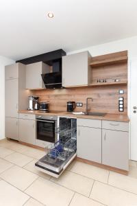 eine Küche mit weißen Schränken und einem Geschirrspüler in der Unterkunft Meerblick-Ferienwohnung Black Pearl in Bensersiel + 22 Fotos
