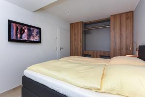 Schlafzimmer mit einem Bett und einem TV an der Wand in der Unterkunft Meerblick-Ferienwohnung Black Pearl in Bensersiel