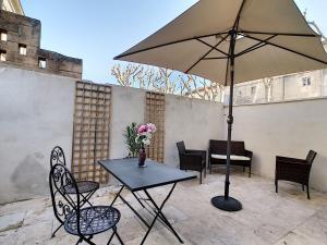 Appartement avec terrasse en centre ville de Saint Remy de Provence في سان ريمي دو بروفنس: طاولة وكراسي مع مظلة على الفناء
