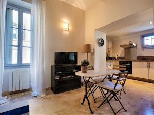 Appartement avec terrasse en centre ville de Saint Remy de Provence في سان ريمي دو بروفنس: غرفة معيشة مع طاولة وكراسي ومطبخ