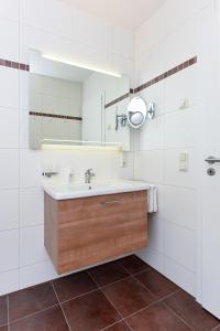 ein Badezimmer mit Waschbecken und Spiegel in der Unterkunft Meerblick-Ferienwohnung Black Pearl in Bensersiel
