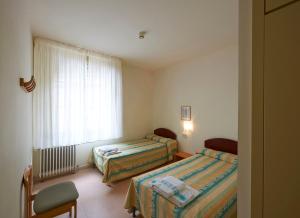 Un dormitorio con dos camas y una ventana y una silla. en Apartamentos Montserrat Abat Marcet, en Montserrat