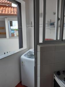 cocina con lavadora y 2 ventanas en Corsário, en Florianópolis