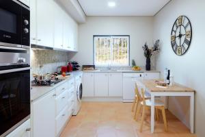 a kitchen with a table and a clock on the wall at Ancão Gardens in Quinta do Lago