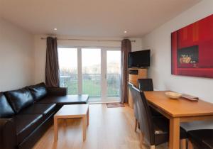 uma sala de estar com um sofá de couro preto e uma mesa em The Lochend Park View Residence em Edimburgo