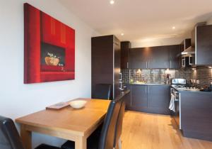 The Lochend Park View Residence في إدنبرة: مطبخ مع طاولة خشبية و لوحة حمراء