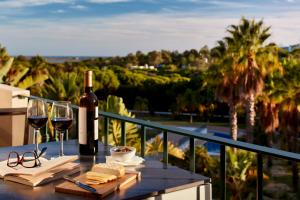 een fles wijn en glazen op een tafel op een balkon bij Ancão Gardens in Quinta do Lago