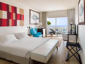 a hotel room with a bed and a desk and chairs at H10 Estepona Palace in Estepona +37 photos