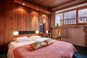 a bedroom with a large bed with wooden walls and windows at Hôtel les Lorès in Val-d'Isère