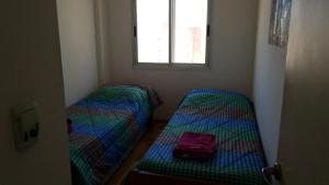 two beds in a room with a suitcase on the floor at Parana in Rosario