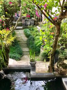 einen Garten mit einem Teich, Bäumen und Blumen in der Unterkunft The Hidden Bali Inn in Ubud