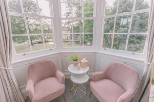 two chairs and a table in a room with windows at Old Bank Rooms in Bourton on the Water